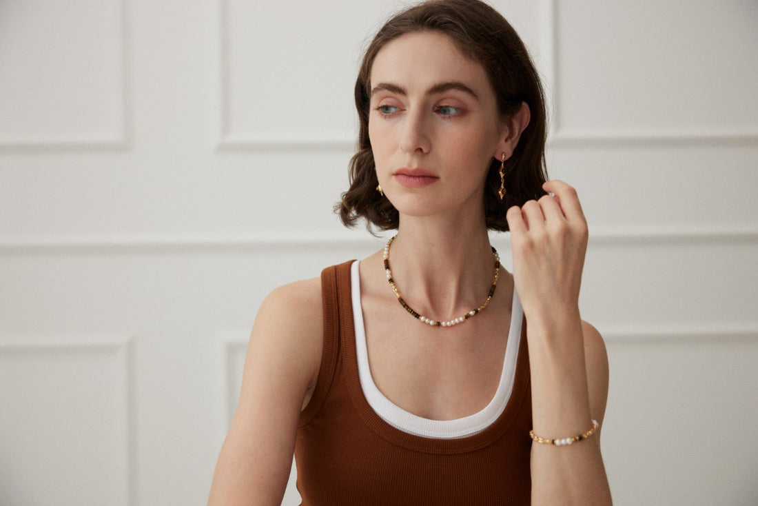 Professional woman wearing delicate pairing necklace, earrings and bracelet with a confident look, demonstrating workplace jewelry styling